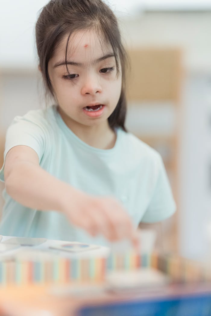 A young girl with Down syndrome joyfully playing indoors, focusing on creativity.