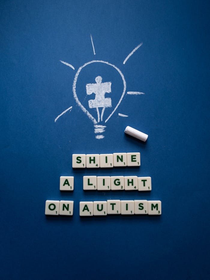 Chalk-drawn light bulb with autism puzzle piece on blue background, promoting awareness.